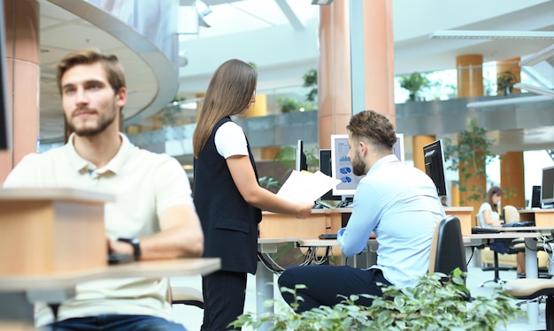 Gruppe junger selbstbewusster Geschäftsleute, die Daten mit Computer analysieren, während sie Zeit im Büro verbringen.