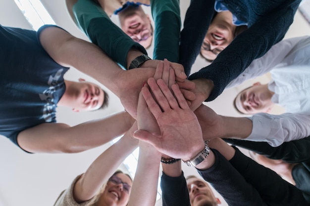 Gruppe junger Studenten im Elektronikklassenzimmer, die erfolgreich abgeschlossenes Projekt feiern, indem sie ihre Hände zusammenhalten, Bildungs- und Technologiekonzept