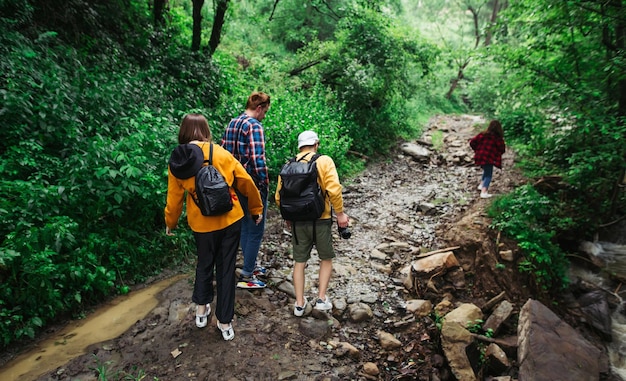 Gruppe junger Wanderer, die auf einem Waldweg in den Bergen in der Nähe eines Baches spazieren