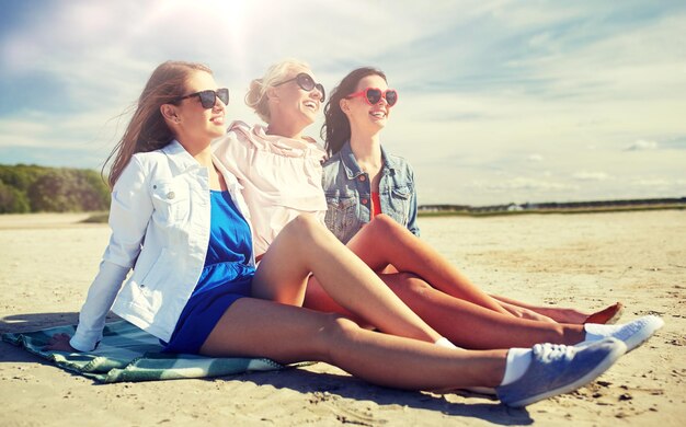 Gruppe lächelnder Frauen in Sonnenbrillen am Strand