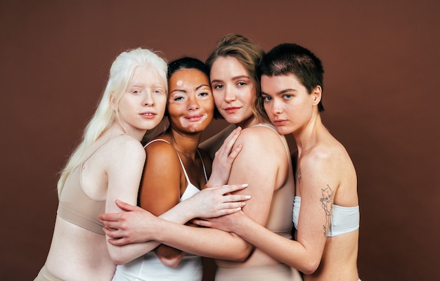 Gruppe multiethnischer Frauen mit unterschiedlicher Haut, die zusammen im Studio posieren. Konzept über Körperpositivität und Selbstakzeptanz