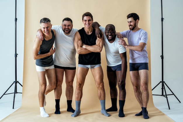 Foto gruppe multiethnischer männer, die für ein körperpositives schönheitsset der männlichen edition posieren. jungs mit unterschiedlichem alter und körper tragen boxerunterwäsche