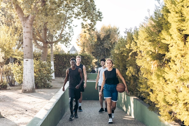 Gruppe multiethnischer Menschen, die mit einem Basketballball zu einem Weg gehen