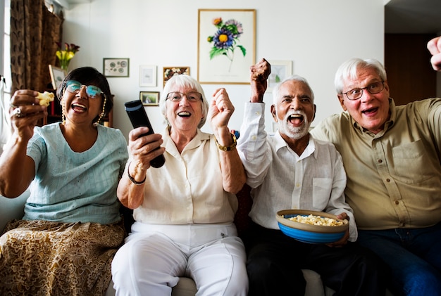 Gruppe nette ältere Freunde, die zusammen sitzen und fernsehen