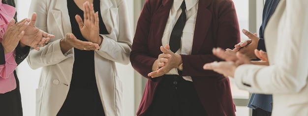 Gruppe nicht erkennbarer Geschäftsfrauen, die sich am Schreibtisch zum Brainstorming treffen. Selbstbewusst geben sie jede Idee und Entscheidung in Memo-Notizen auf den Schreibtisch und klatschen dann glücklich in die Hände.