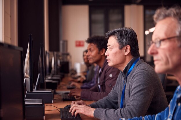 Gruppe reifer erwachsener Studenten in der Klasse, die an Computern in der College-Bibliothek arbeiten