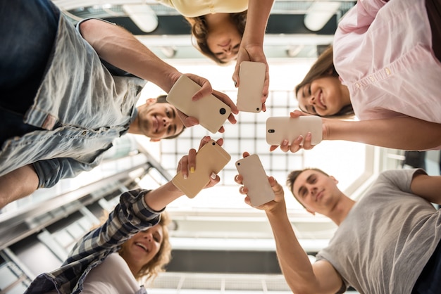 Gruppe studenten, die im kreis stehen und telefone verwenden.