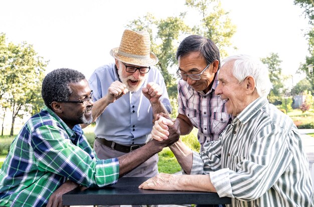 Gruppe von älteren Freunden, die im Park Armdrücken spielen