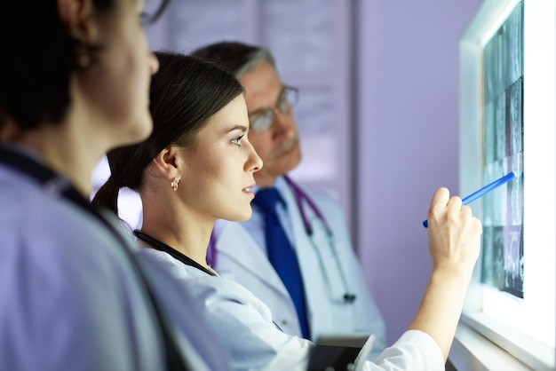 Gruppe von Ärzten, die Röntgenaufnahmen in einer Klinik untersuchen und an eine Diagnose denken