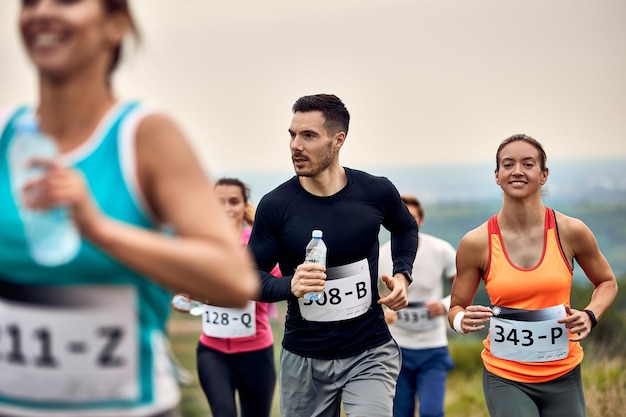 Gruppe von Athleten, die Marathon in der Natur laufen Der Fokus liegt auf jungen Paaren