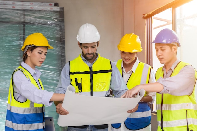 Gruppe von Bauarbeiterteams, die gemeinsam diskutieren und den Grundriss bei der Baustellenplanung betrachten