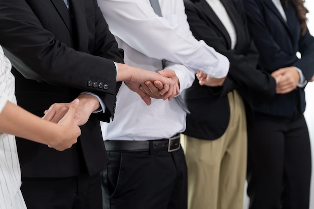 Gruppe von Büroangestellten, die Hand in Hand halten, um die Harmonie am Arbeitsplatz zu fördern
