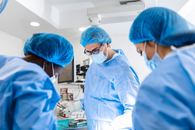 Gruppe von Chirurgen im Operationssaal mit chirurgischen Geräten