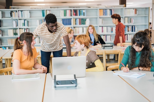 Gruppe von College-Studenten in der Bibliothek, die zusammen studieren und Notizen austauschen