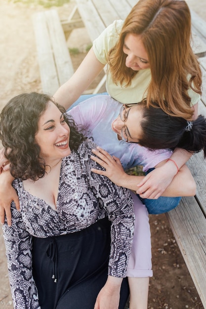 Foto gruppe von drei glücklichen freundinnen, die sich umarmen und lächeln, frauen genießen freundschaft, schwesternschaftsfrauen.