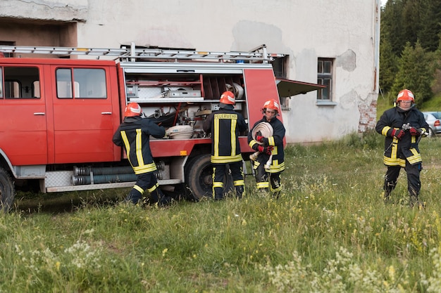 Gruppe von Feuerwehrleuten, die nach einer gut durchgeführten Rettungsaktion zuversichtlich stehen. Feuerwehrleute bereit für den Notdienst. Foto in hoher Qualität