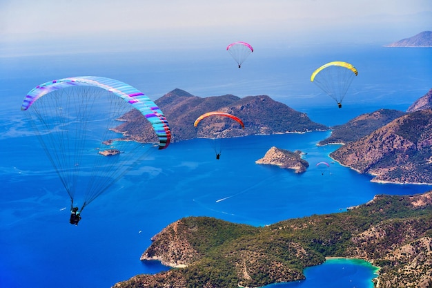 Gruppe von fliegenden Gleitschirmen über Berginseln im blauen Meer Ölüdeniz Türkei