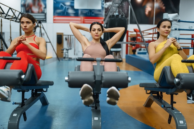 Gruppe von Frauen, die abs Übung in der Turnhalle, Vorderansicht tun. Menschen auf Fitness-Training im Sportverein, sportliche Mädchen in Sportbekleidung beim Training in Innenräumen