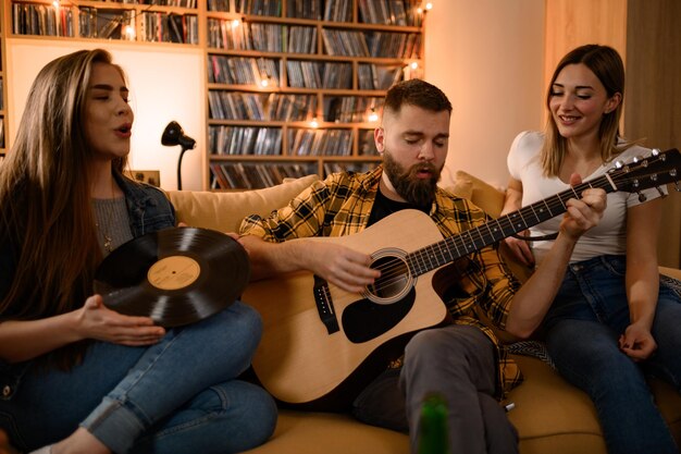 Gruppe von Freunden auf einer Hausparty, die Gitarre spielt und Spaß hat