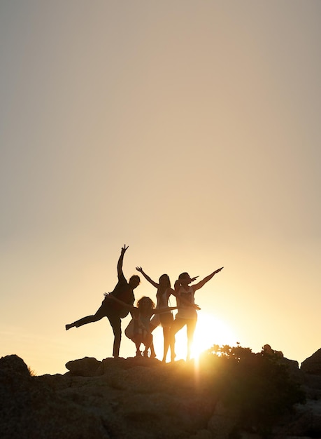 Gruppe von Freunden, die bei Sonnenuntergang auf Felsen stehen und Spaß im Sommerurlaub haben und Freundschaft feiern