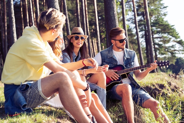 Gruppe von Freunden, die bei Sonnenuntergang feiern und Musik hören.