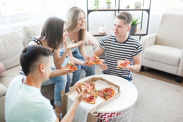Gruppe von Freunden, die drinnen Pizza essen