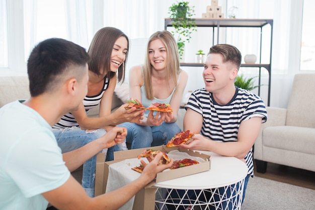 Gruppe von Freunden, die drinnen Pizza essen