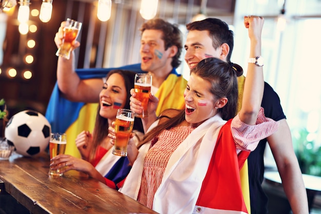 Gruppe von Freunden, die Fußballspiel in der Kneipe gucken