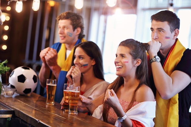 Gruppe von Freunden, die Fußballspiel in der Kneipe gucken