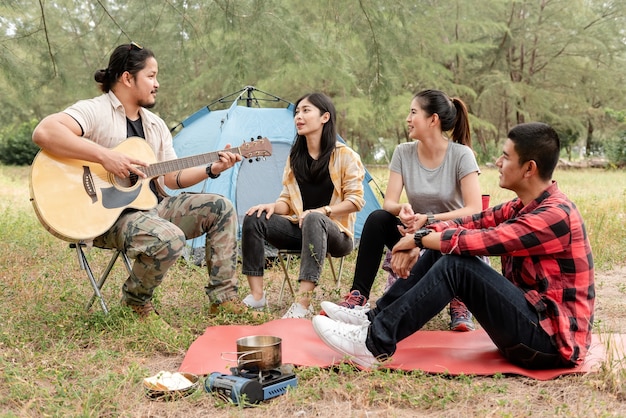 Gruppe von Freunden, die Gitarre im Park spielen