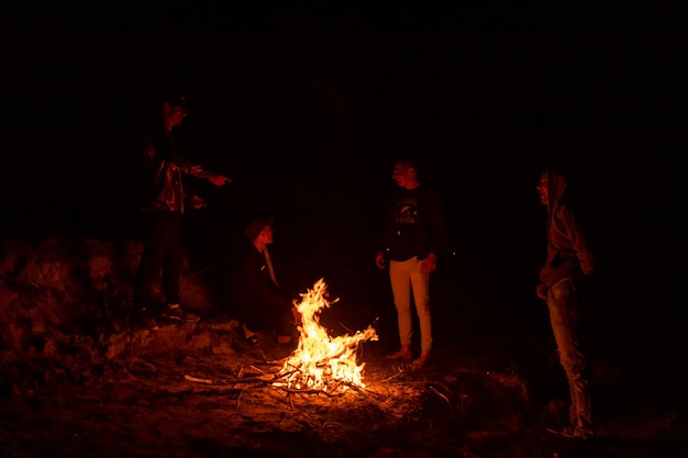 Gruppe von Freunden, die nachts um ein Lagerfeuer plaudern.