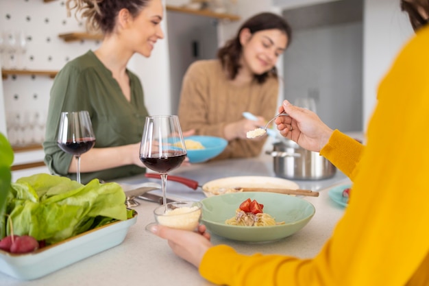 Foto gruppe von freunden, die nudeln zusammen in der küche essen