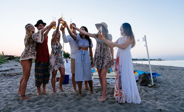 Gruppe von Freunden, die Party am Strand zur Sonnenuntergangszeit machen