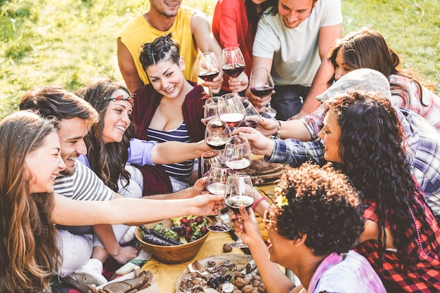 Gruppe von Freunden, die Picknick genießen, während Rotwein trinken und Snacks Vorspeise im Freien essen