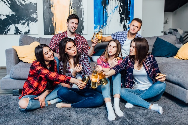 Gruppe von Freunden, die sich mit Bier entspannen und eine gute Zeit in der Wohnung haben.