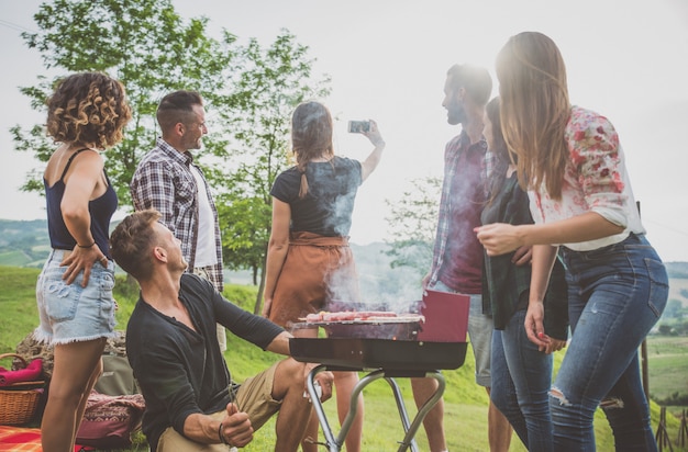 Foto gruppe von freunden, die zeit damit verbringen, ein picknick und einen grill zu machen