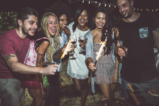 Gruppe von Freunden, die zum Abendessen im Hinterhof grillen