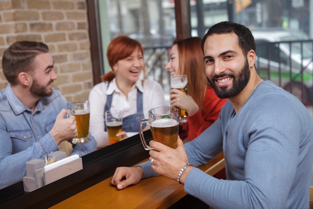 Gruppe von Freunden, die zusammen Bier in der Kneipe trinken