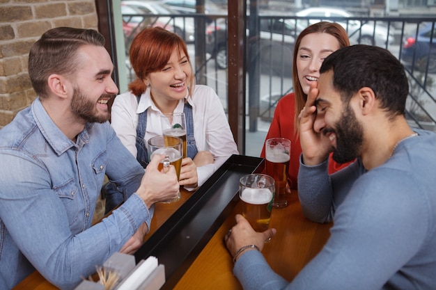 Gruppe von Freunden, die zusammen Bier in der Kneipe trinken