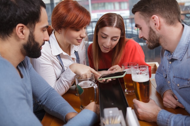 Gruppe von Freunden, die zusammen Bier in der Kneipe trinken