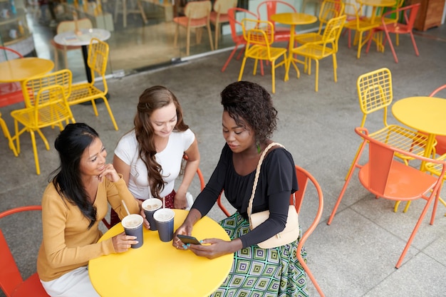 Gruppe von Freundinnen, die am Cafétisch sitzen, Eistee trinken und Neuigkeiten und Trends diskutieren