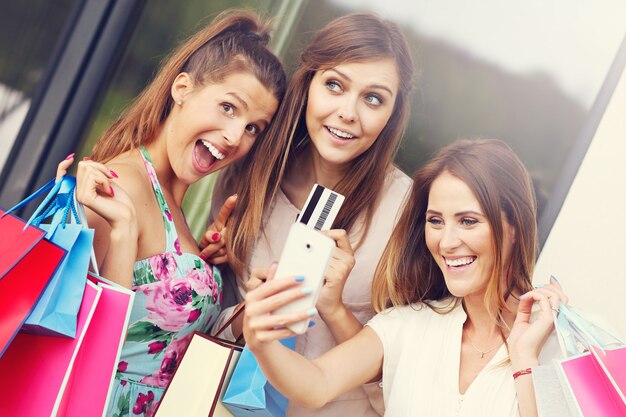 Gruppe von Freundinnen, die mit Kreditkarte und Smartphone in der Stadt einkaufen