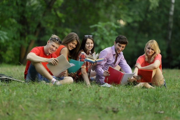 Gruppe von Freundschülern, die auf dem Gras im Park sitzen