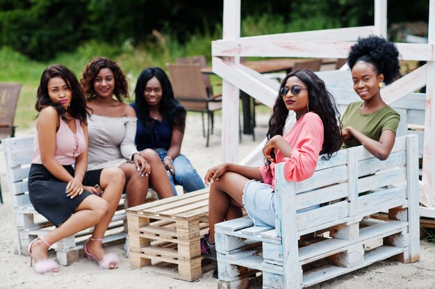 Gruppe von fünf Frauen, die am Strand außerhalb des Cafés entspannen