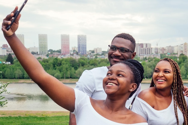 gruppe von fünf freunden weiblich und männlich, die selfie auf dem kamera-smartphone machen und spaß im freien lebensstil in der nähe des sees haben