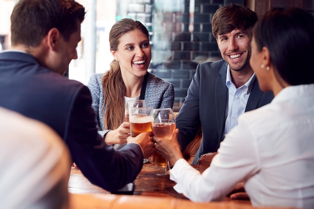 Gruppe von Geschäftskollegen, die einen Toast machen, während sie sich zu Getränken treffen und nach der Arbeit in der Bar Kontakte knüpfen