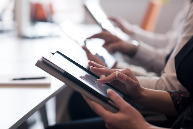 Gruppe von Geschäftsleuten beim Treffen mit einem Tablet-Computer in einem modernen, hellen Startup-Büro