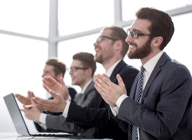 Gruppe von Geschäftsleuten, die applaudieren, an seinem Deskphoto mit Kopierraum sitzen