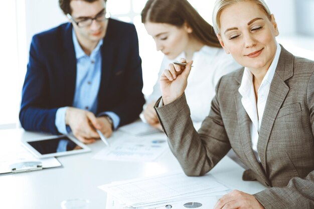 Gruppe von Geschäftsleuten, die Fragen bei einem Treffen in einem modernen Büro diskutieren. Kopfschuss der Geschäftsfrau bei Verhandlungen. Teamwork, Partnerschaft und Geschäftskonzept.