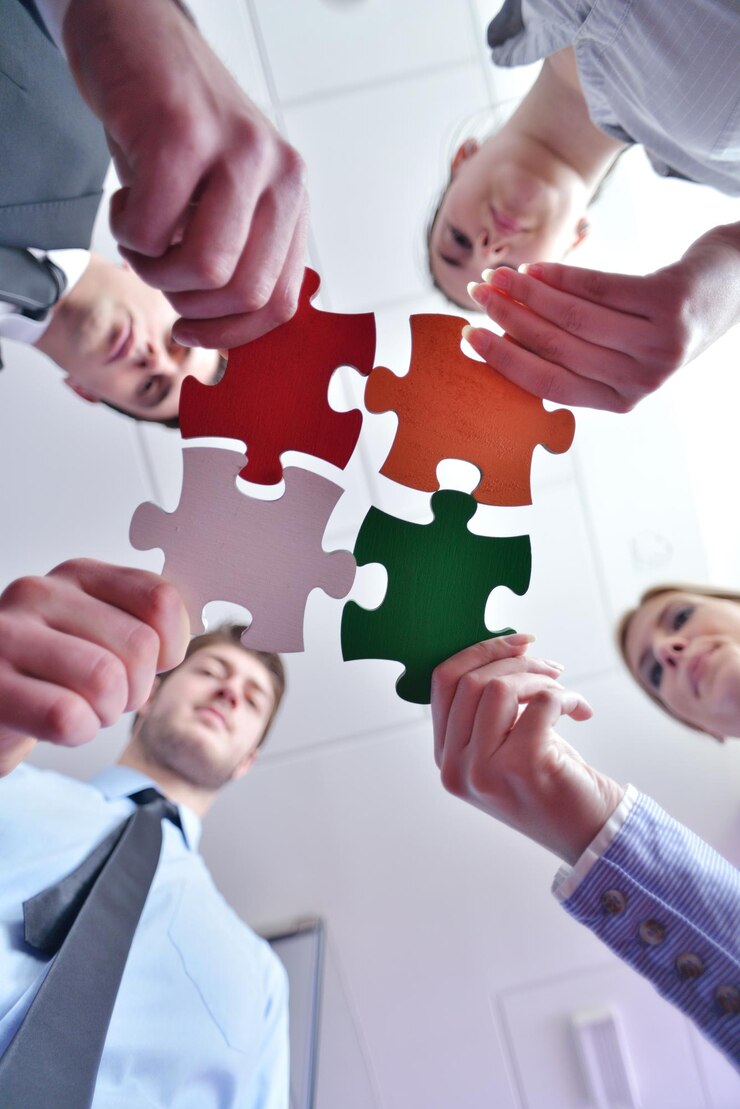 Foto gruppe von geschäftsleuten, die puzzles zusammenstellen und teamunterstützungs- und hilfekonzept darstellen